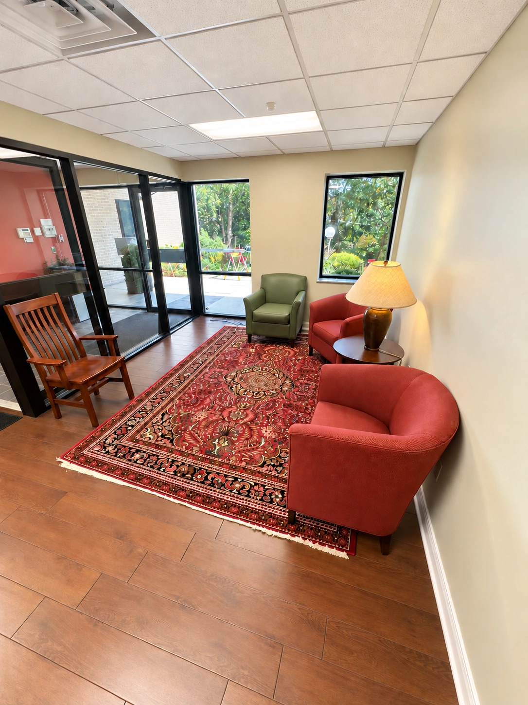 Client waiting area with upholstered chairs, a patterned rug and windows beside the front vestibule.