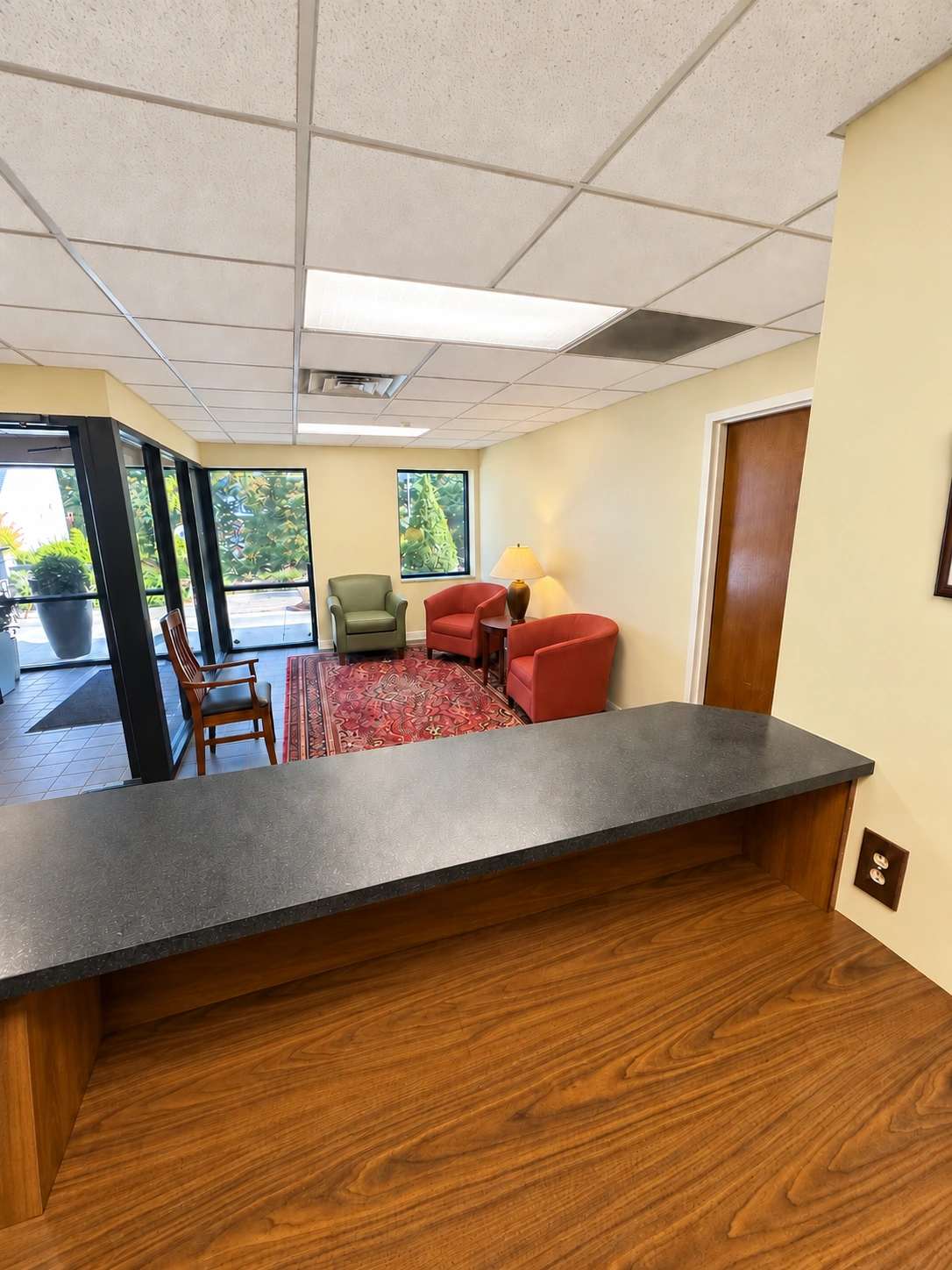 View across the reception counter toward the waiting chairs and glass front vestibule.