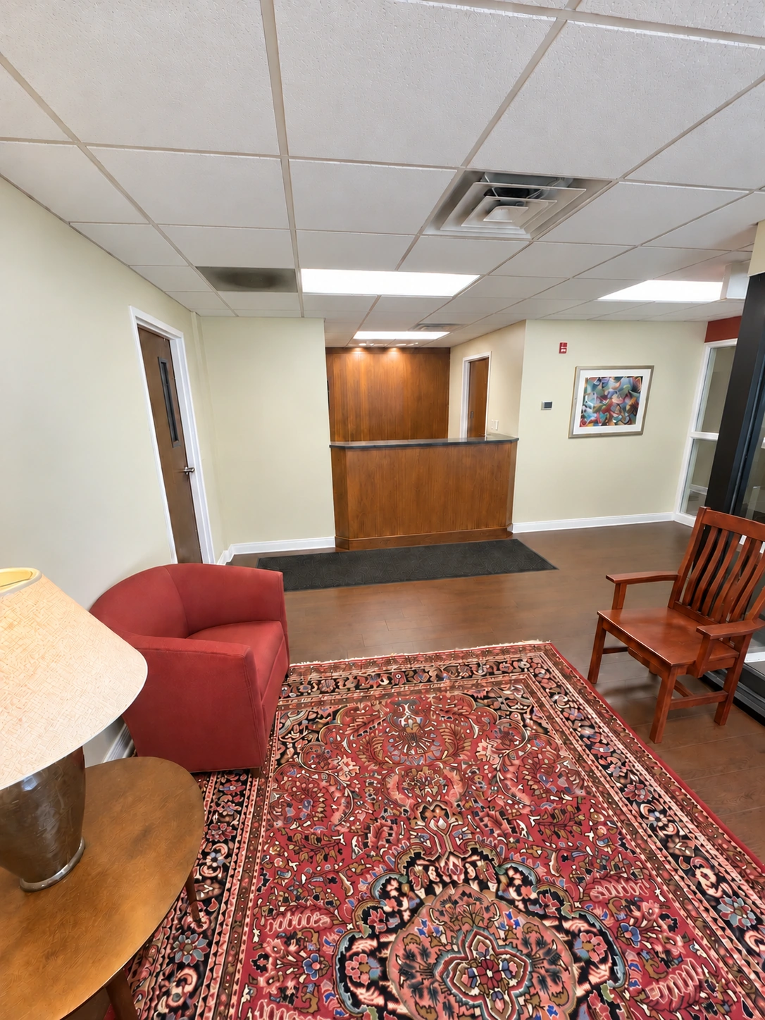 Dedicated reception counter, waiting-area chairs and a patterned rug in the first-floor suite.