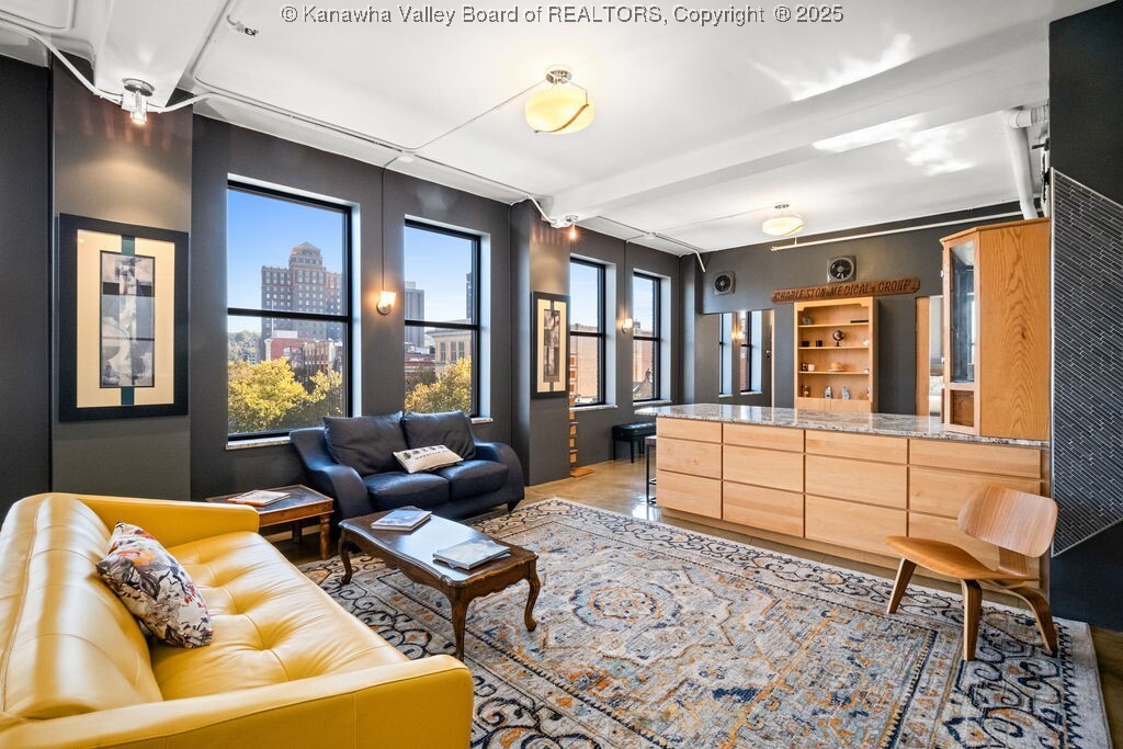 Suite 400 living area with downtown windows, exposed white ceiling structure, concrete floors and custom maple cabinetry